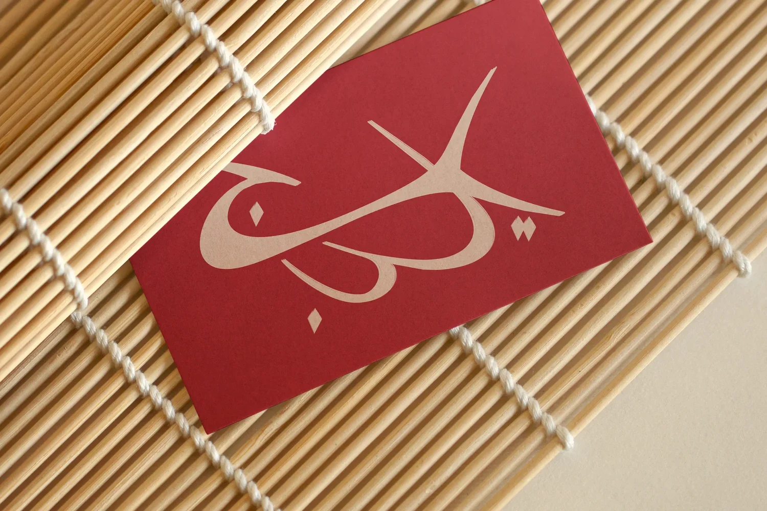 YBJ — business card in Henné and Sable on a bamboo mat, first tactile application of the logo, mockup by StudioKus