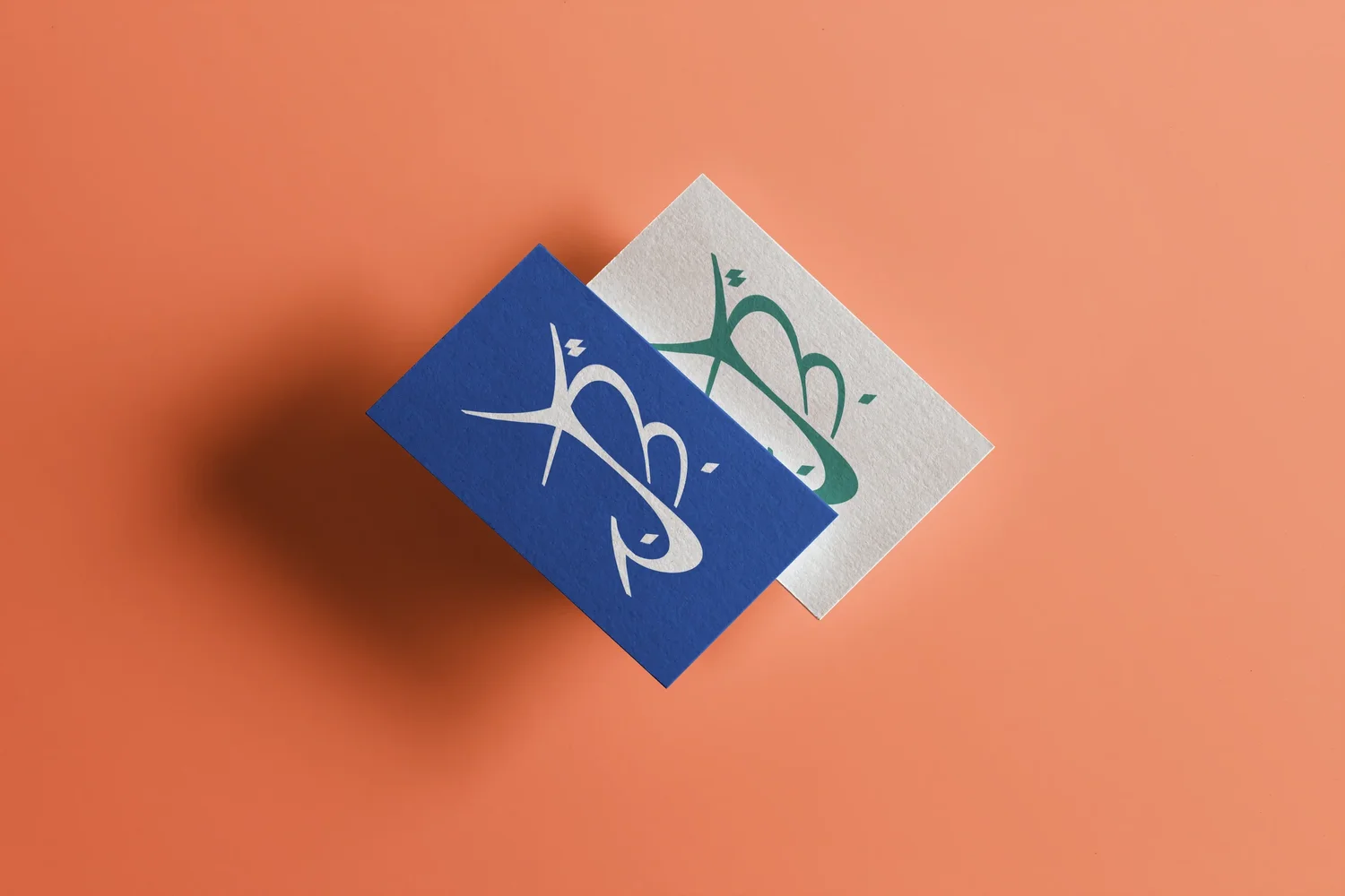YBJ — two business cards, one in Atlantique and Sable, the other in Oasis on cream, on a Terre background, demonstrating the colour pairs, mockup by StudioKus