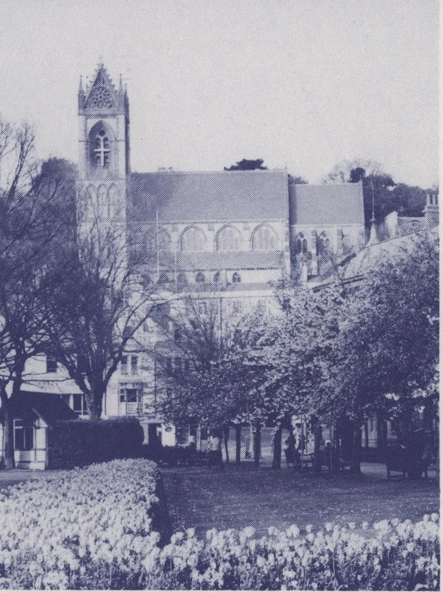 The Church of St John the Evangelist, Torquay, seen from the gardens with its tall tower rising above the surrounding rooftops and trees