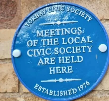 Torbay Civic Society blue plaque reading Meetings of the Local Civic Society are held here, established 1976, photographed on a stone wall