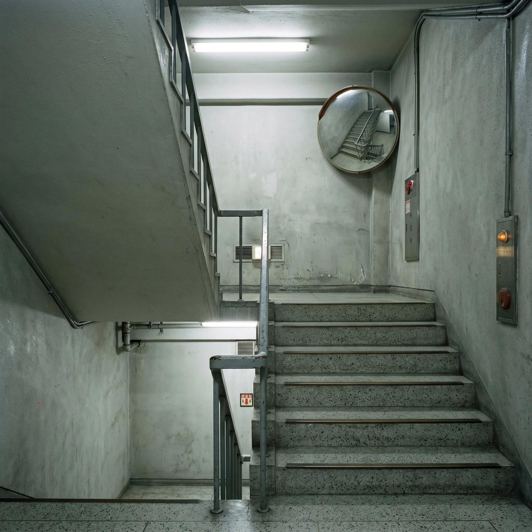 An empty stairwell reflected in a round safety mirror.