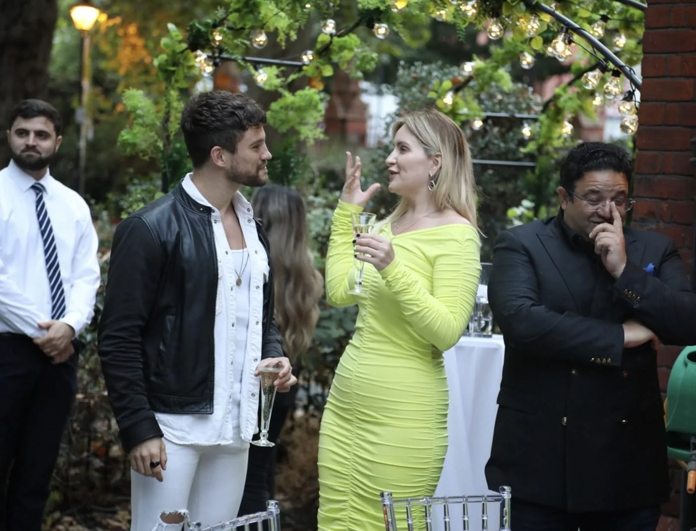 Layla in a lime green dress talking with guests under festoon lights
