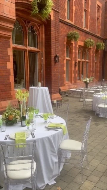 Round tables dressed in white and lime in a red brick courtyard