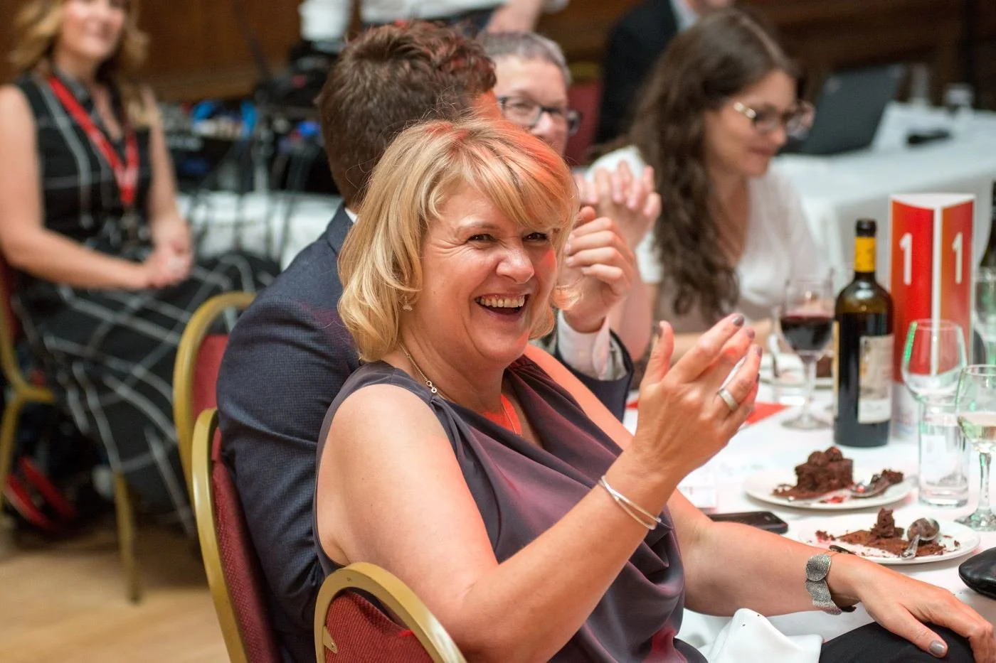 A guest laughing and applauding at a dinner table