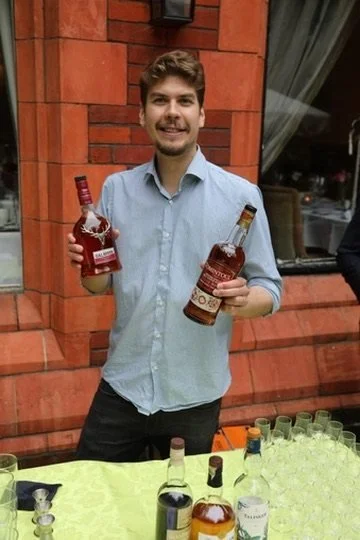 A host holding two bottles of whisky at the tasting table