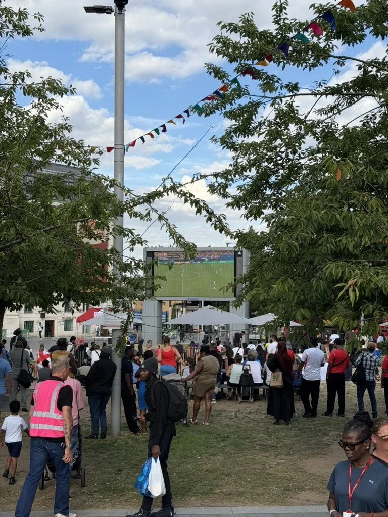 The match on the big screen framed by trees and bunting