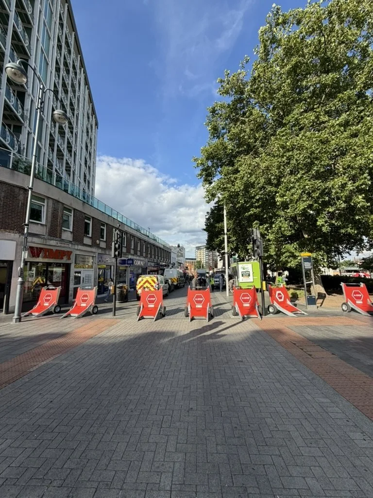A line of red vehicle barriers closing the approach road