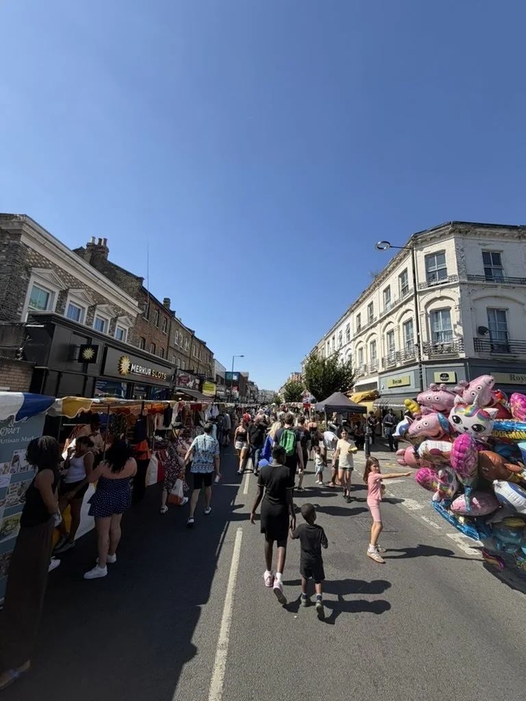 Crowds walking between market stalls on a traffic free North End Road