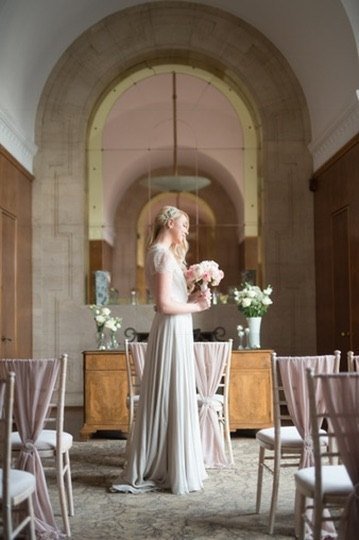 A bride holding pink roses beneath a mirrored arch