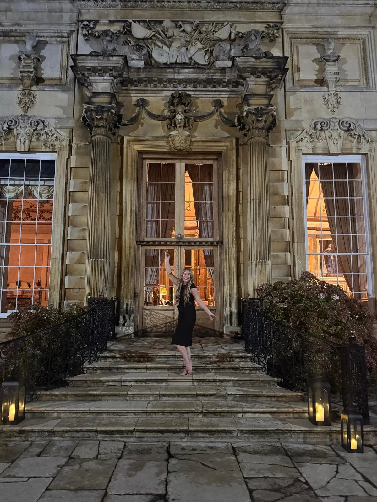 Layla on the steps of Drayton House at night, lit by lanterns