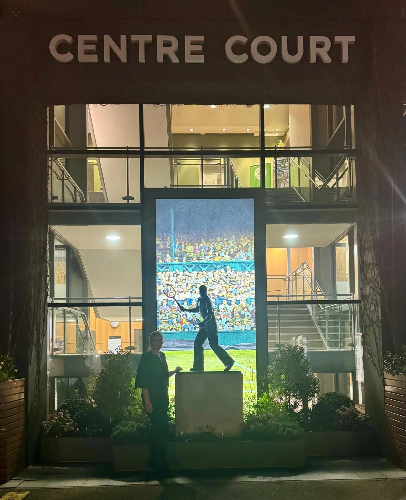 Layla beside the statue outside Centre Court at night