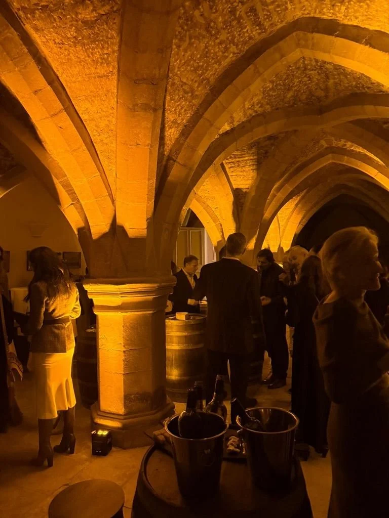 Guests with wine barrels under a vaulted stone ceiling