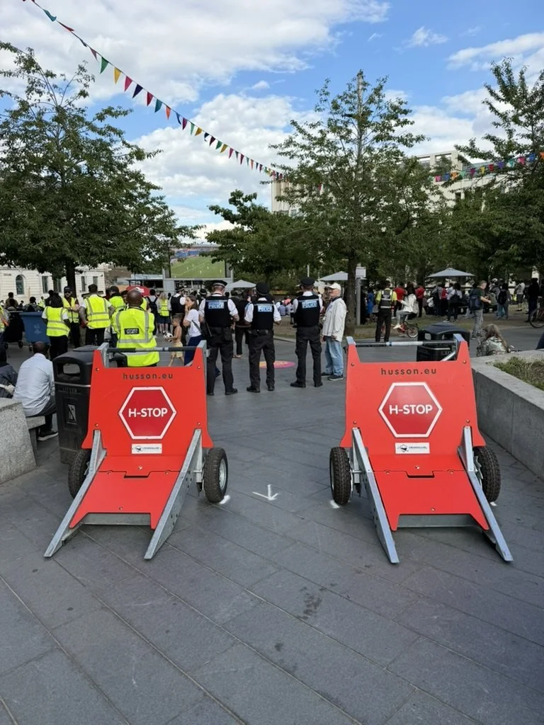 Hostile vehicle barriers at an entrance with police and stewards behind