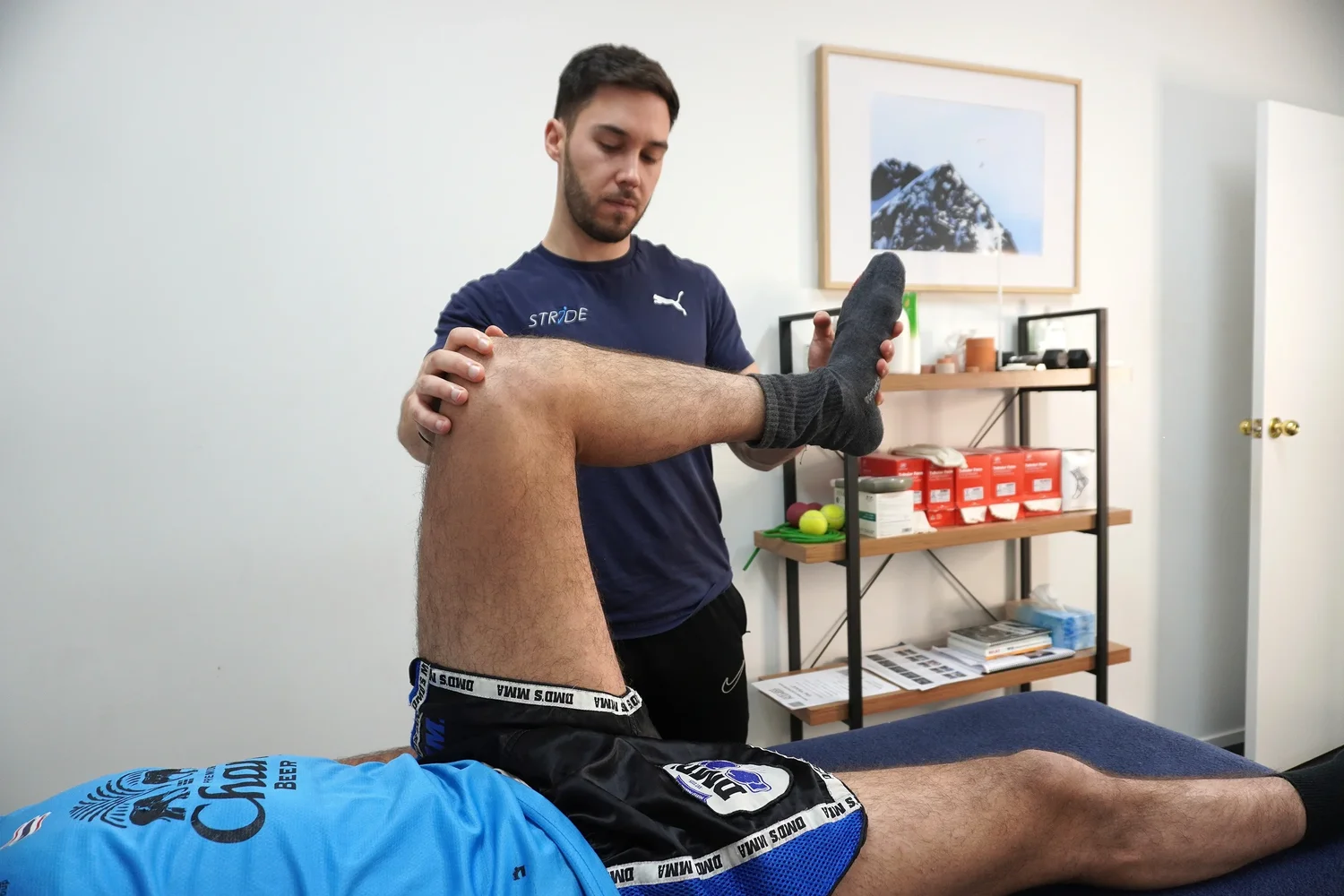 Tom Yeung assessing a combat sports athlete's knee and hip range at the Moonee Ponds clinic