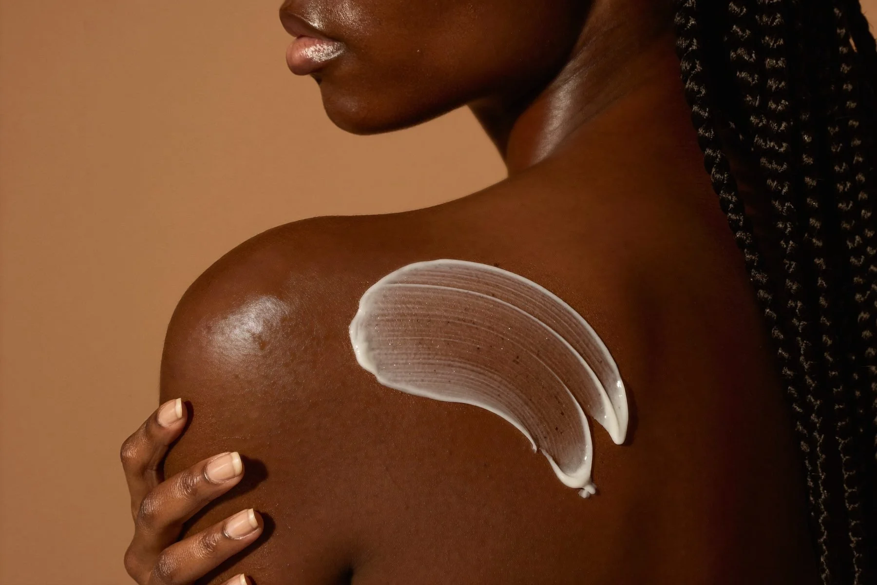 Woman smoothing body butter across her shoulder