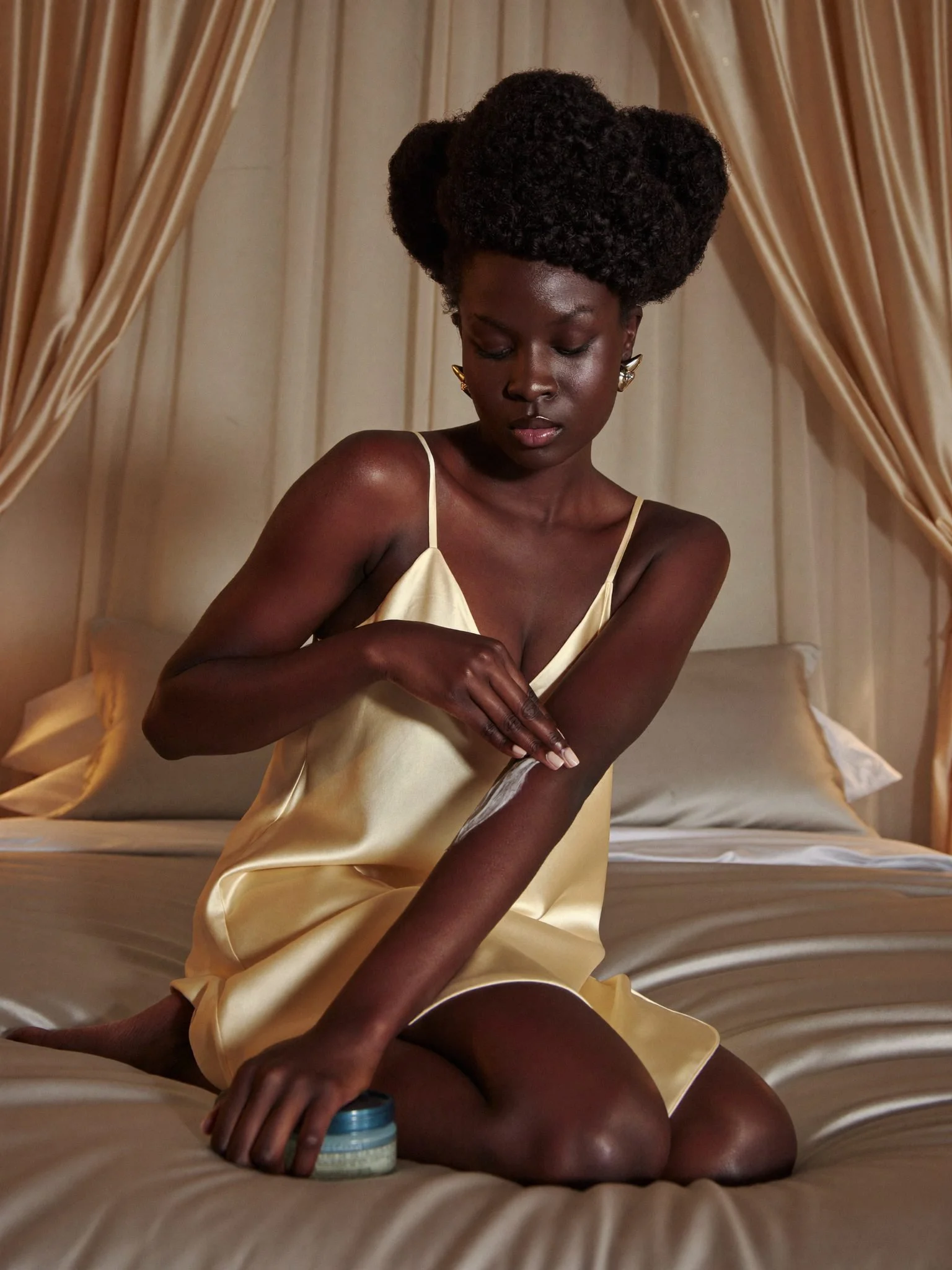 Black woman in a satin slip applying body butter