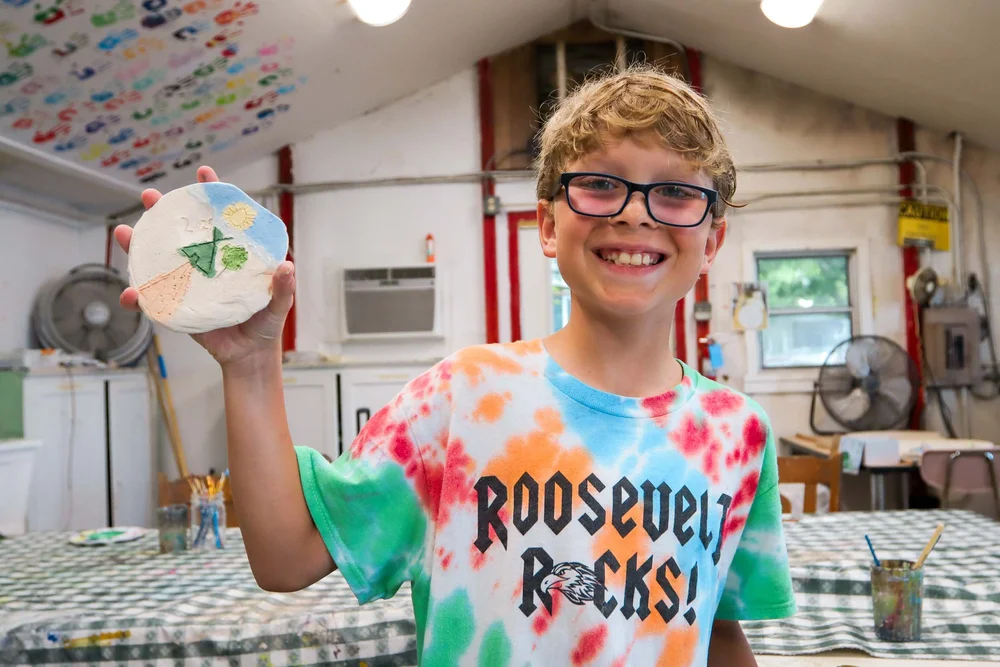 Boy smiling while holding his ceramics project
