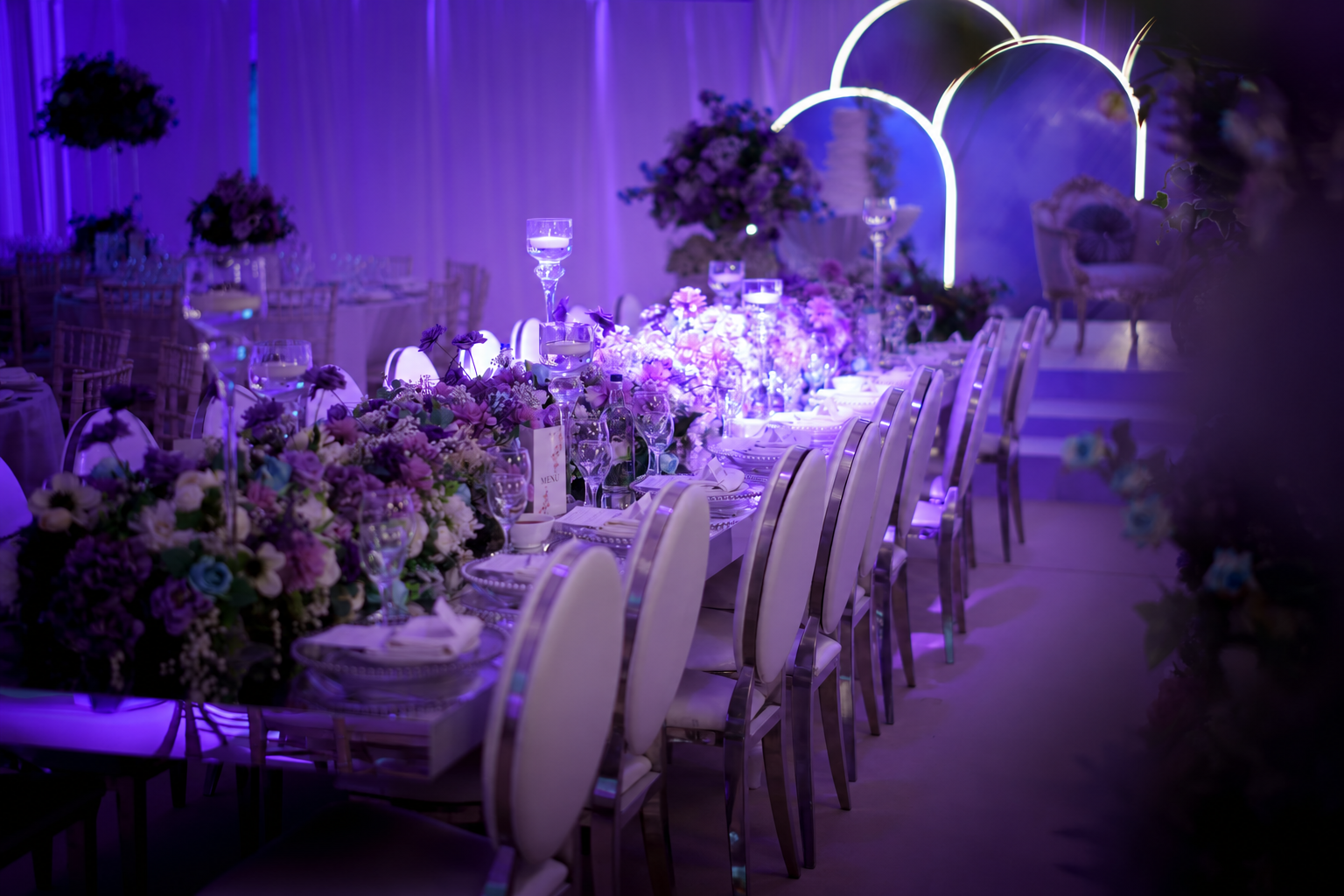 Floral reception table under purple event lighting