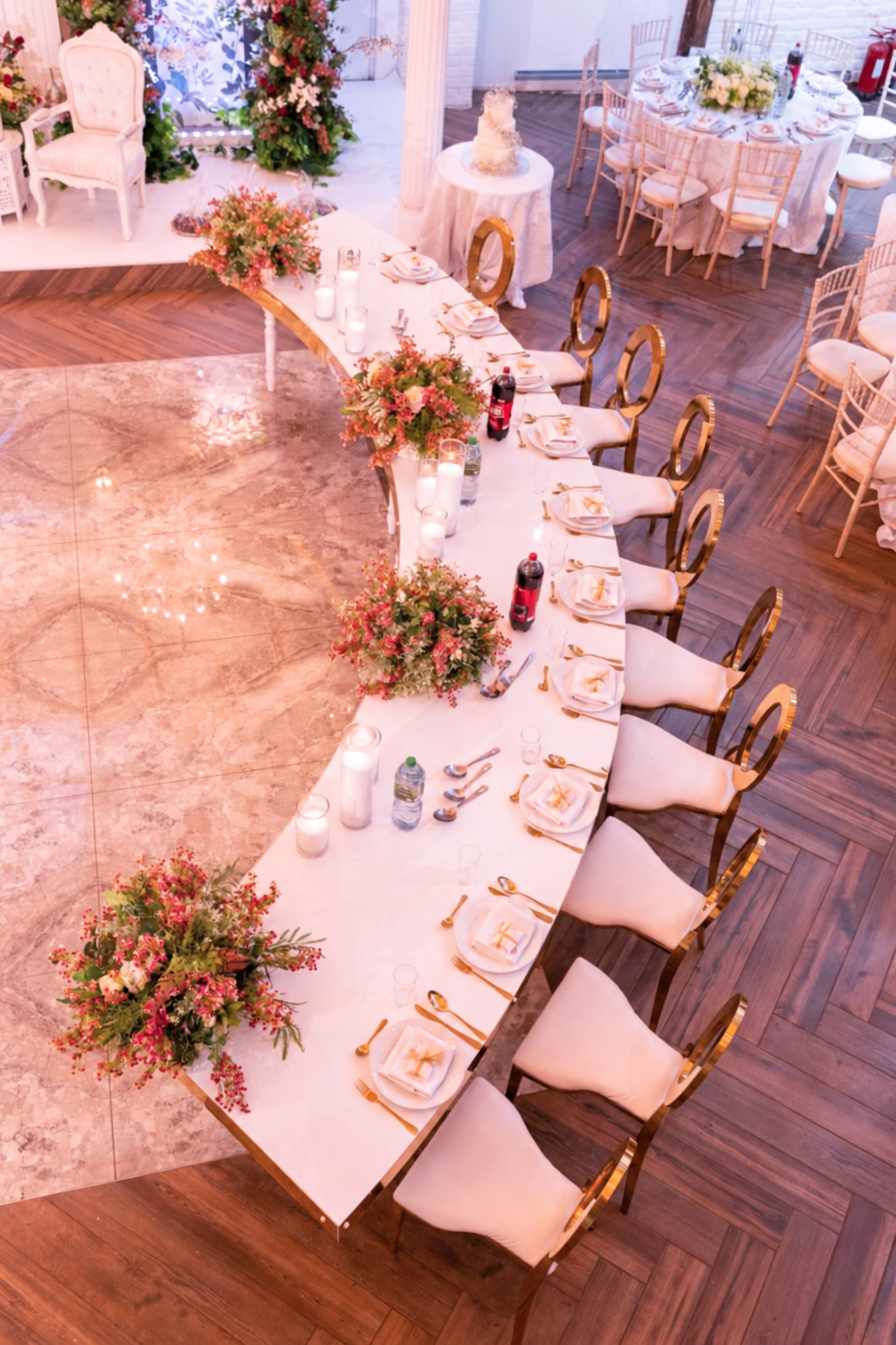 Curved head table with gold chairs and pink flowers