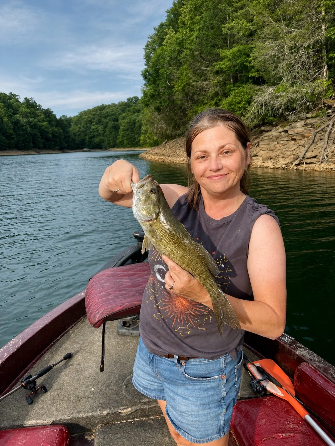 Rachel Stepek holding a bass while spending time on freshwater for wildlife artwork reference