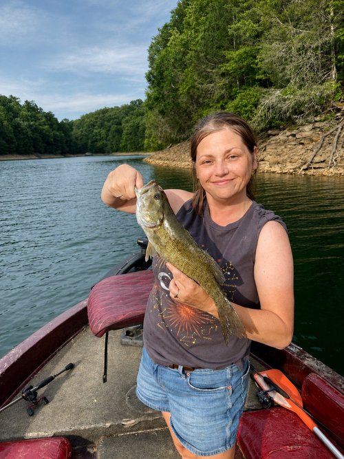 Rachel Stepek holding a bass while spending time on freshwater for wildlife artwork reference