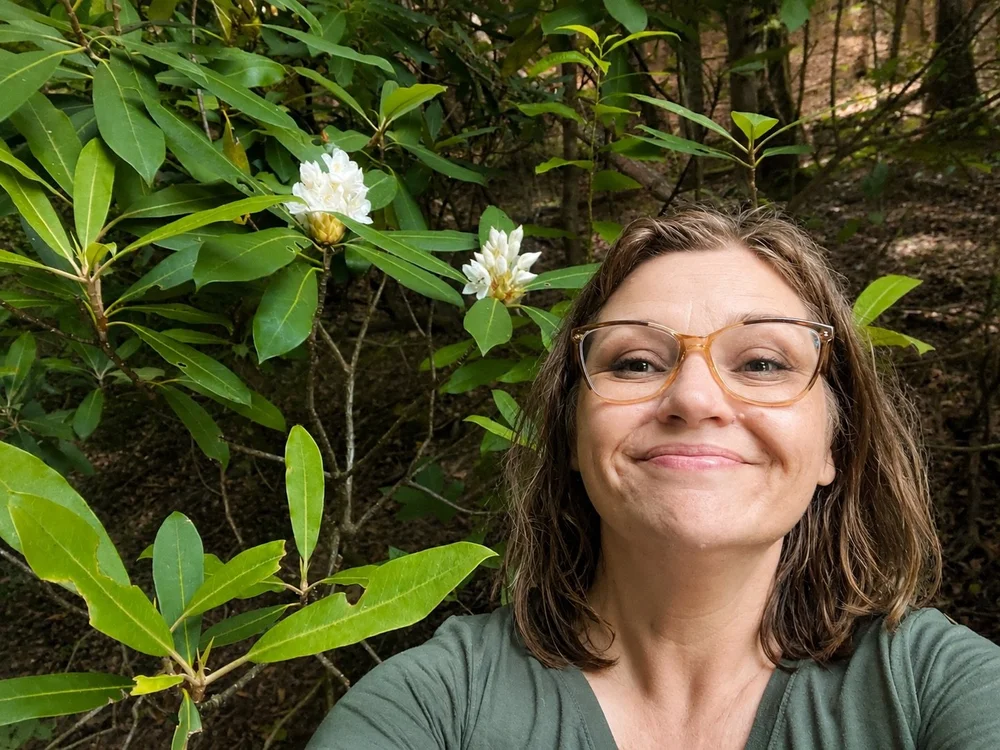 Rachel Stepek in the woods beside blooming native rhododendron