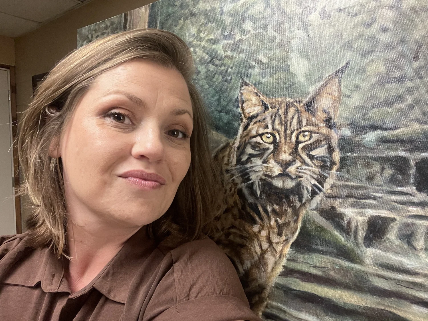 Rachel Stepek beside an original bobcat oil painting