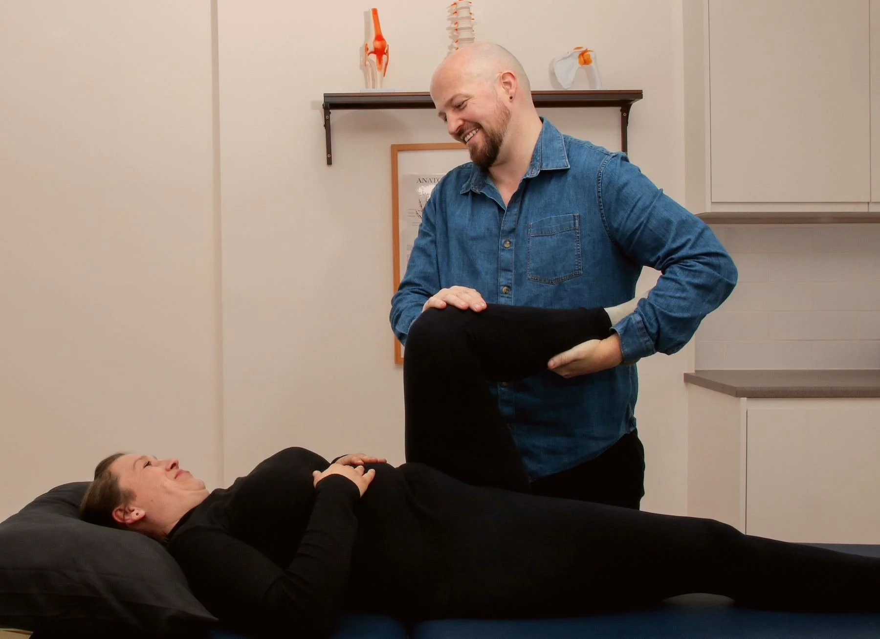Ben Peters assessing hip and leg movement during a postnatal appointment