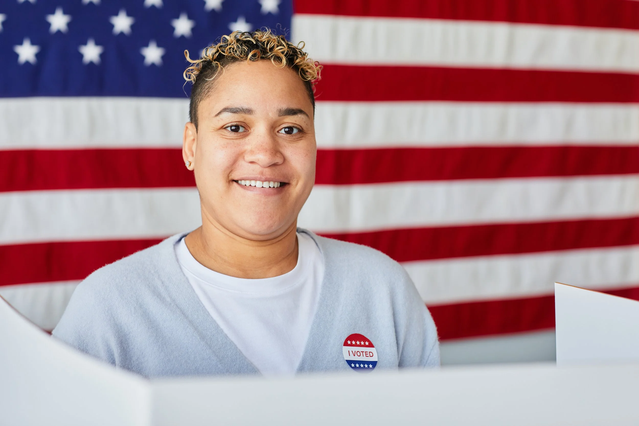 Smiling woman with voting sticker at polling place