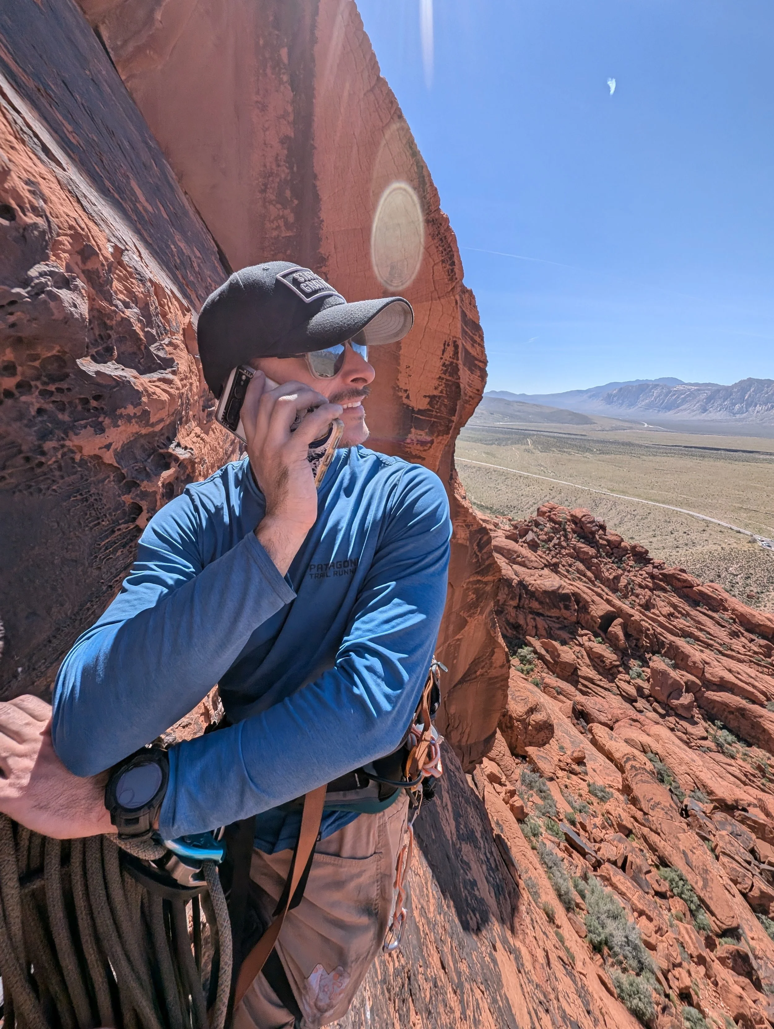 Chris Coles taking a call mid-climb
