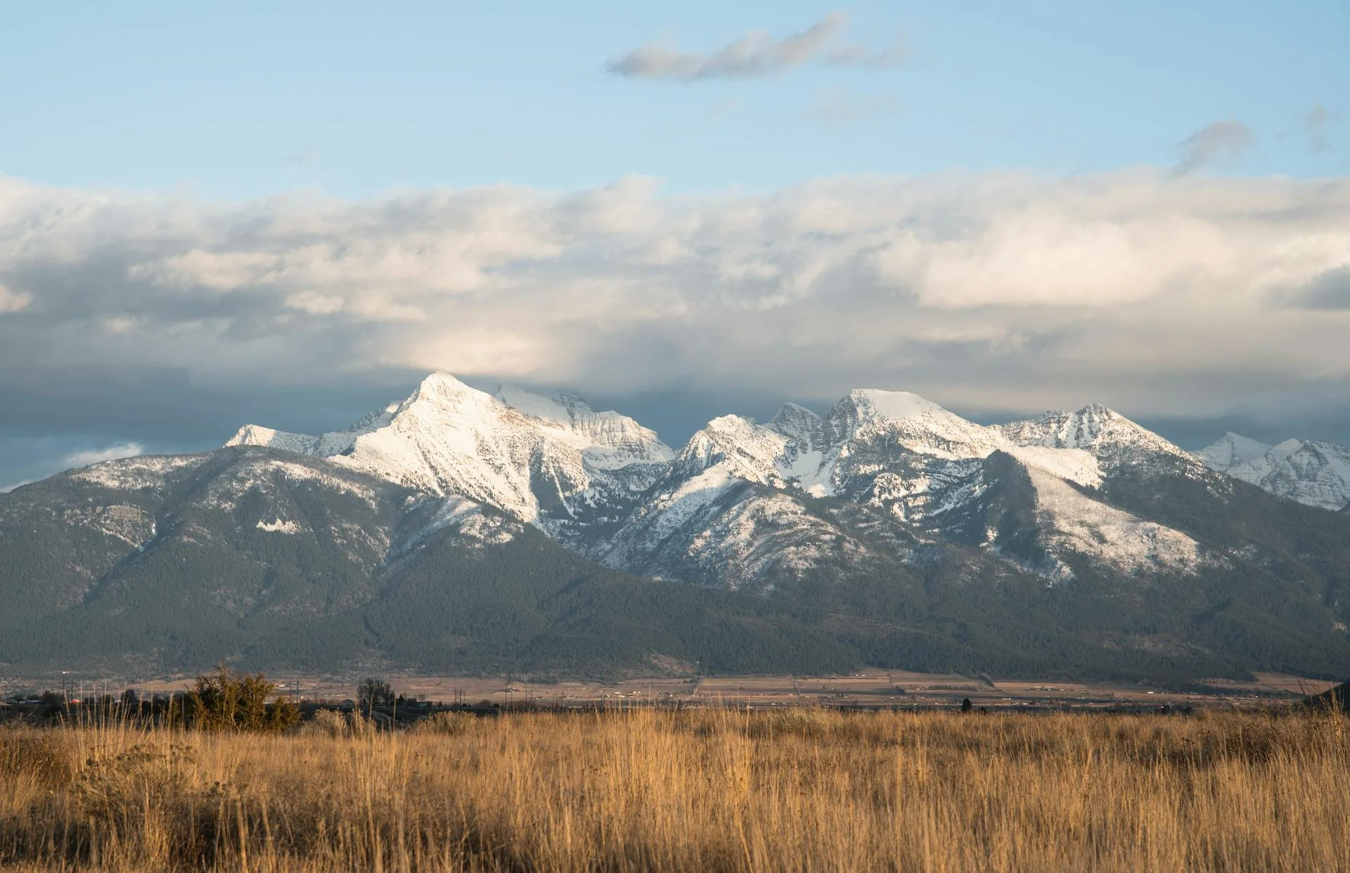 Open grassland beneath snow-capped Rocky Mountain peaks in Montana — the Big Sky Country wilderness Big Sky Fire Defense serves with CitroTech wildfire protection.