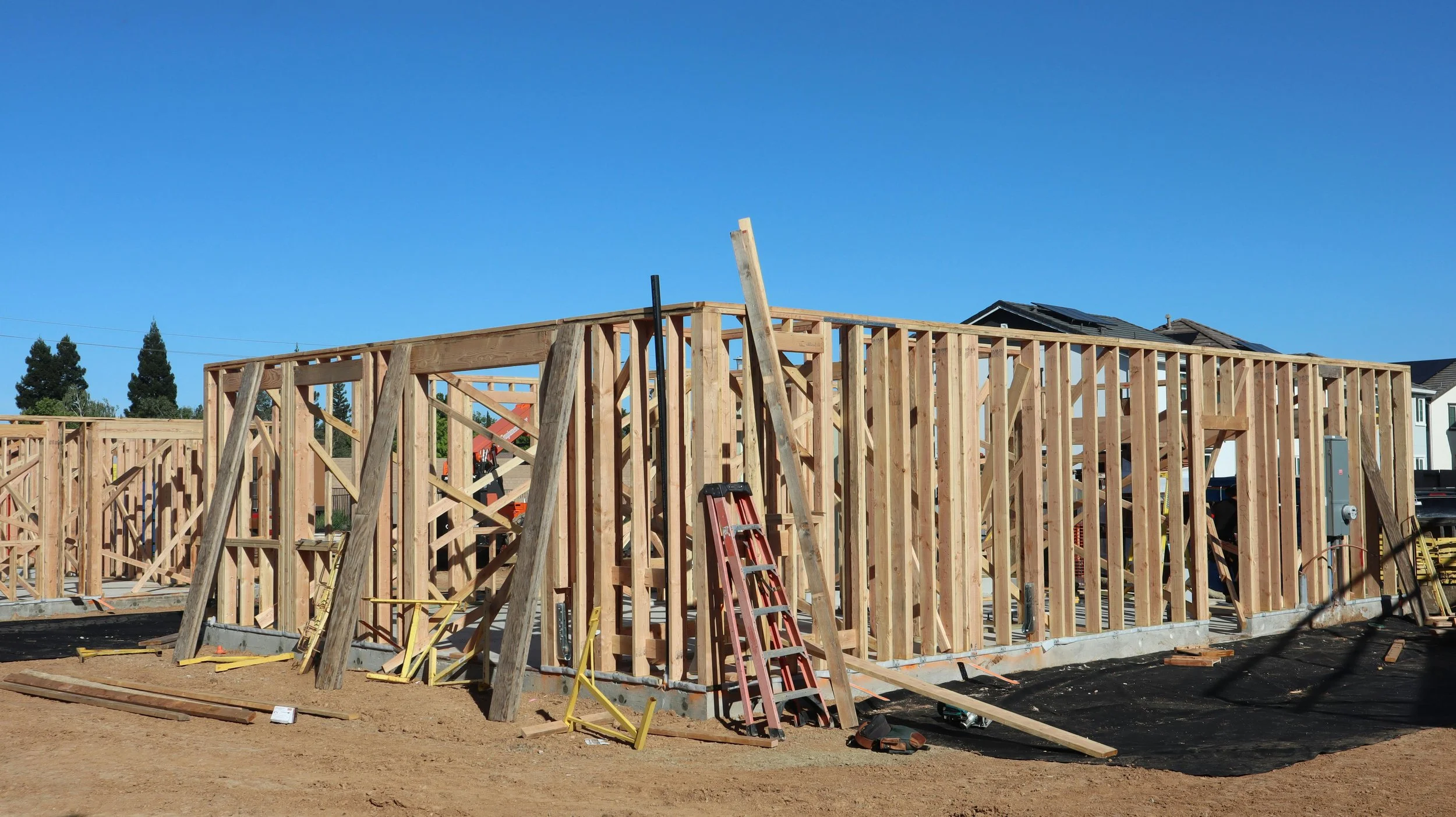 A custom home under construction with exposed timber framing — the stage when wildfire-resilient choices like Class A roofing, ember-resistant detailing, and treated framing lumber are least expensive to build in