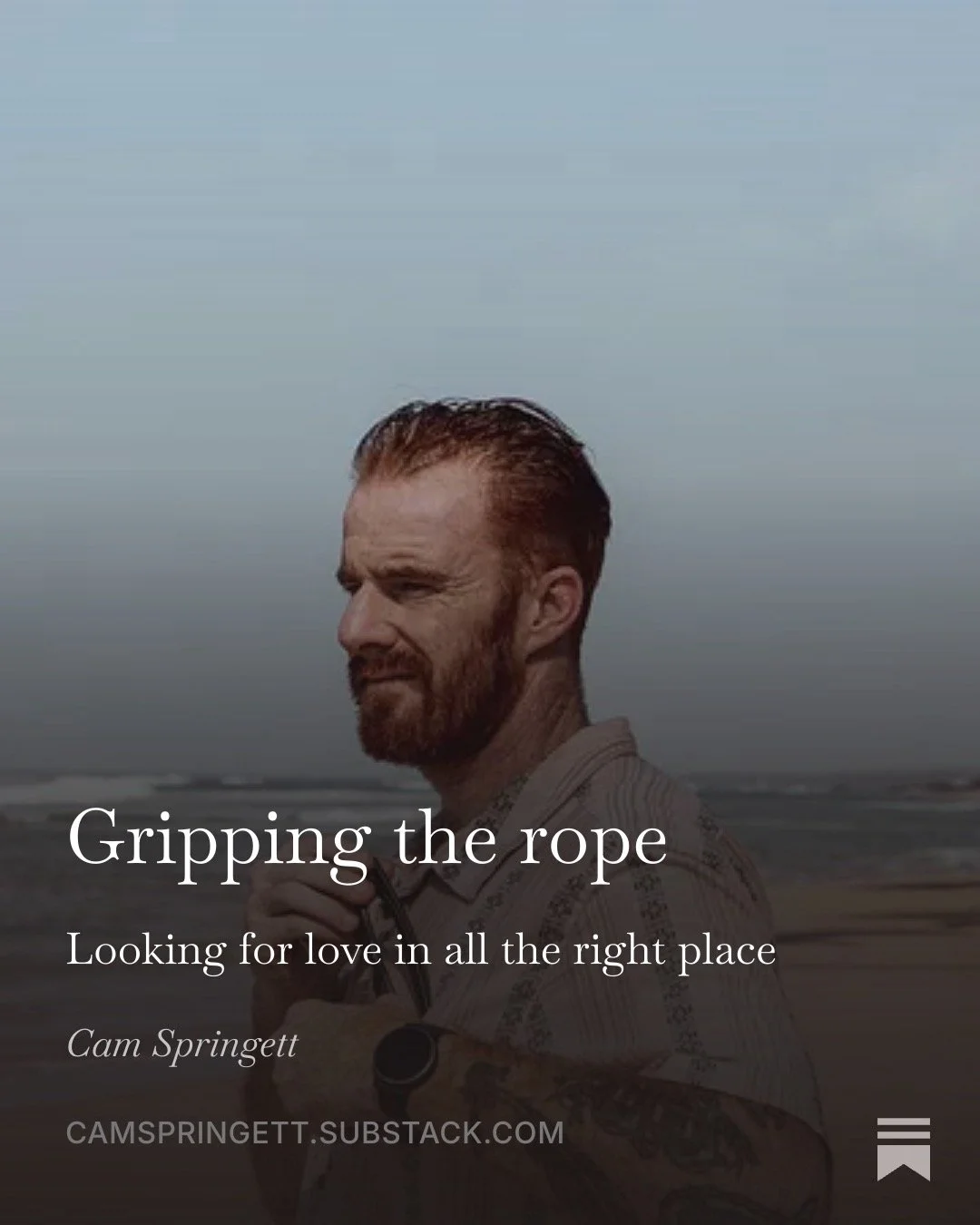 Gripping the rope. Looking for love in all the right place. Cam Springett standing on a beach, looking out along the shoreline.