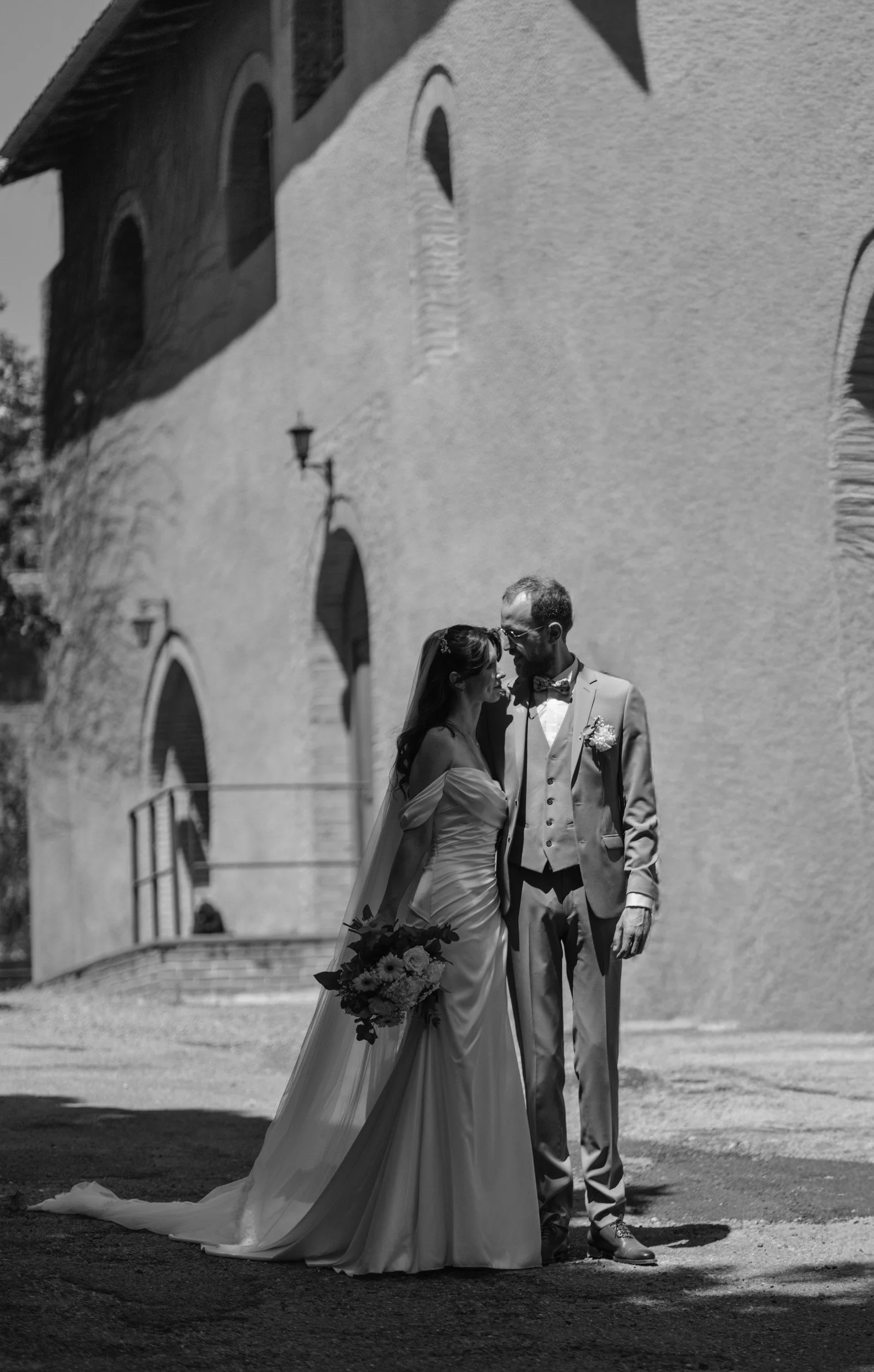 Les mariés près du porche de l’église, en noir et blanc
