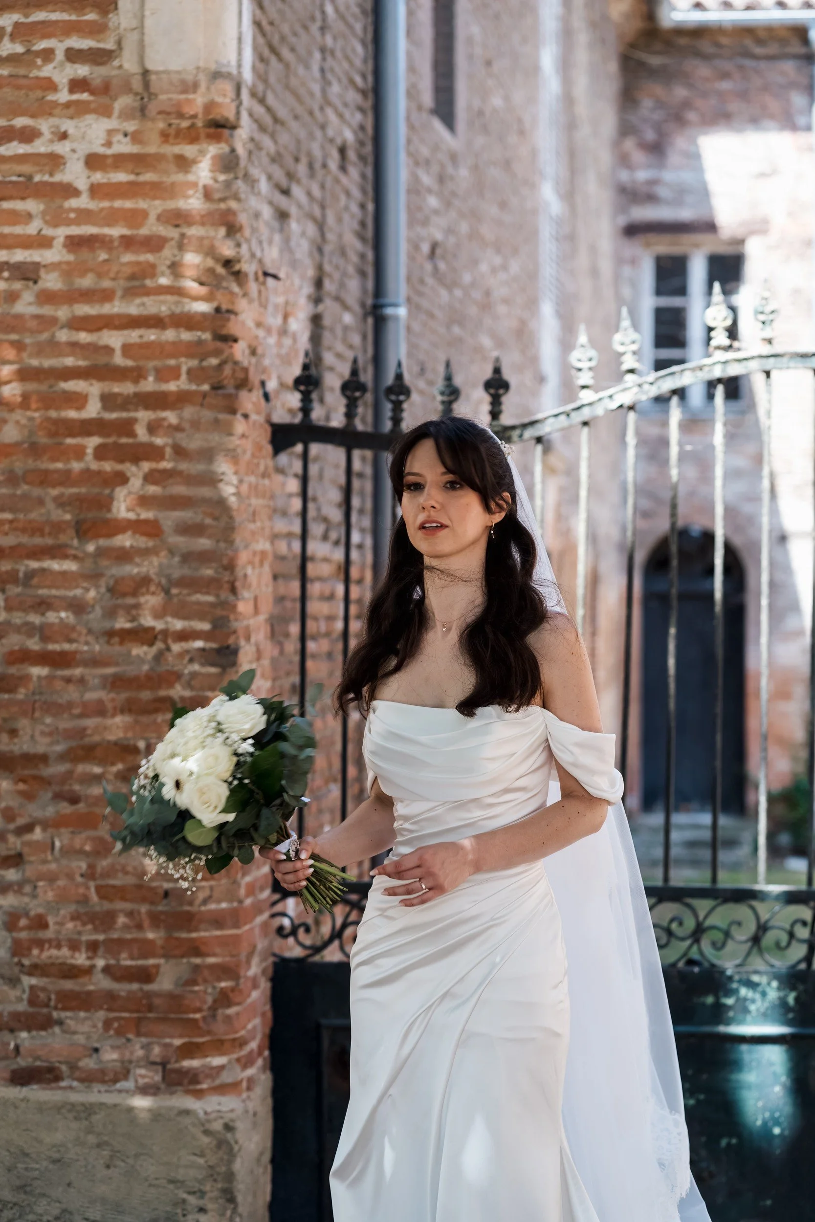 Portrait de la mariée et de son bouquet devant une grille
