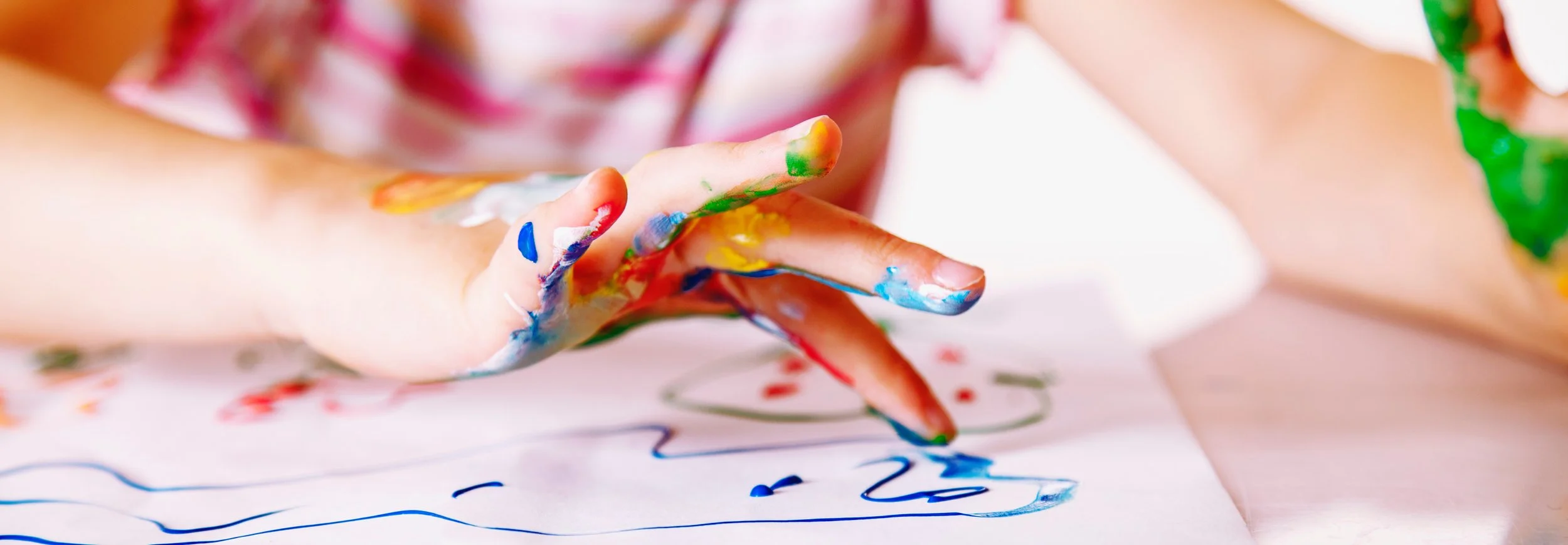 Child painting with bright colors, representing creative development