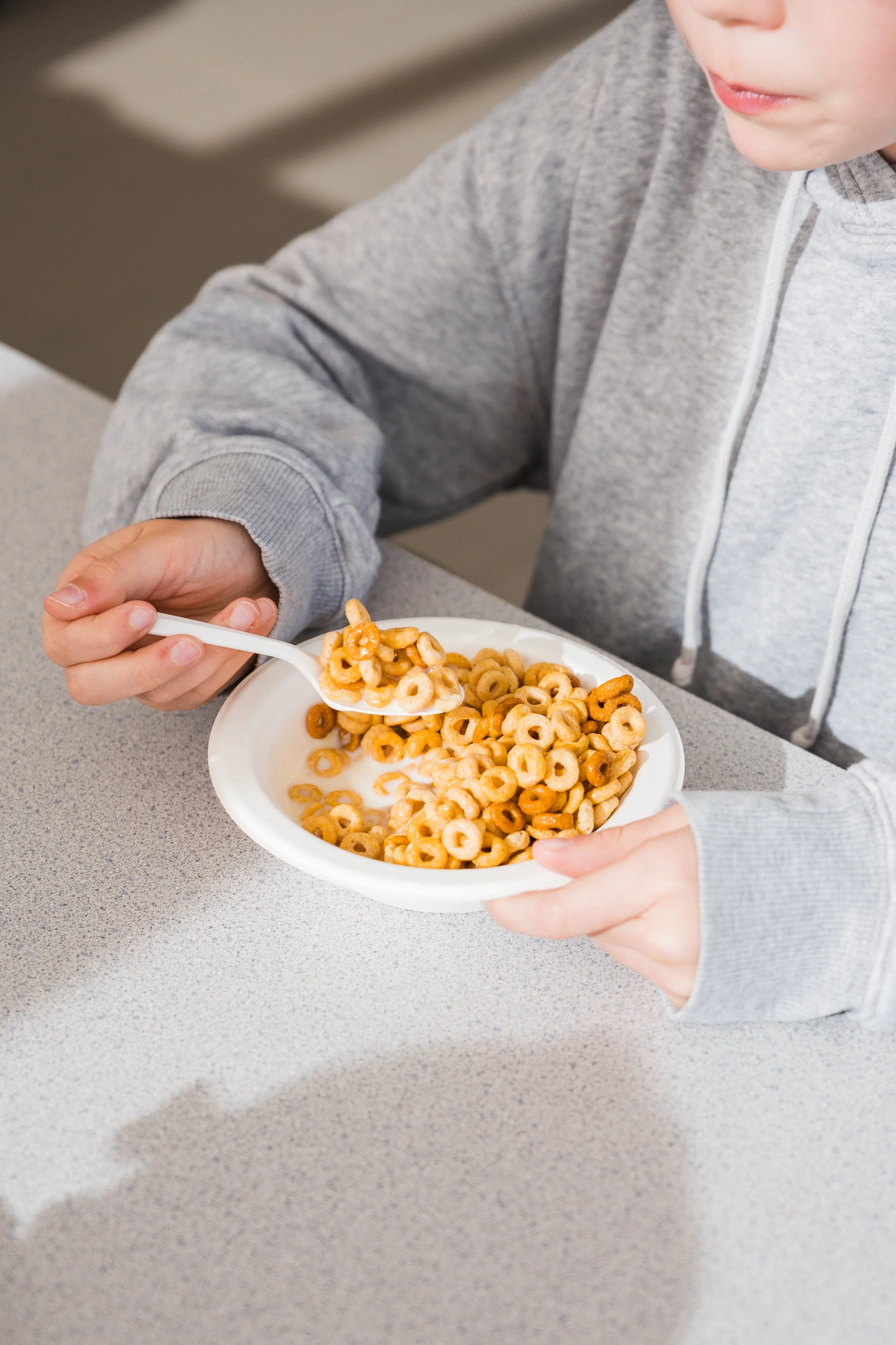 A young student eating a bowl of cereal