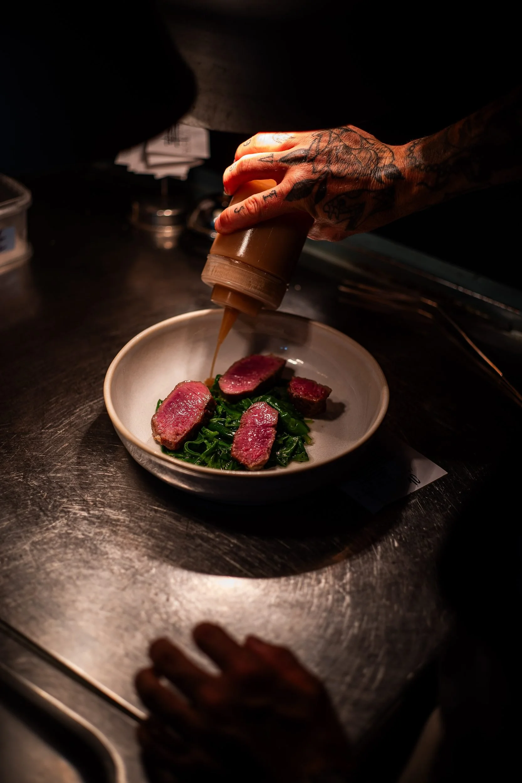 Chef plating duck breast greens sauce