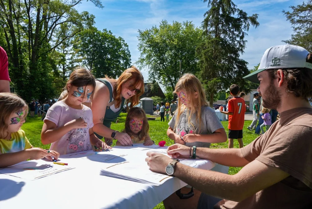 Kids coloring at a community table outdoors