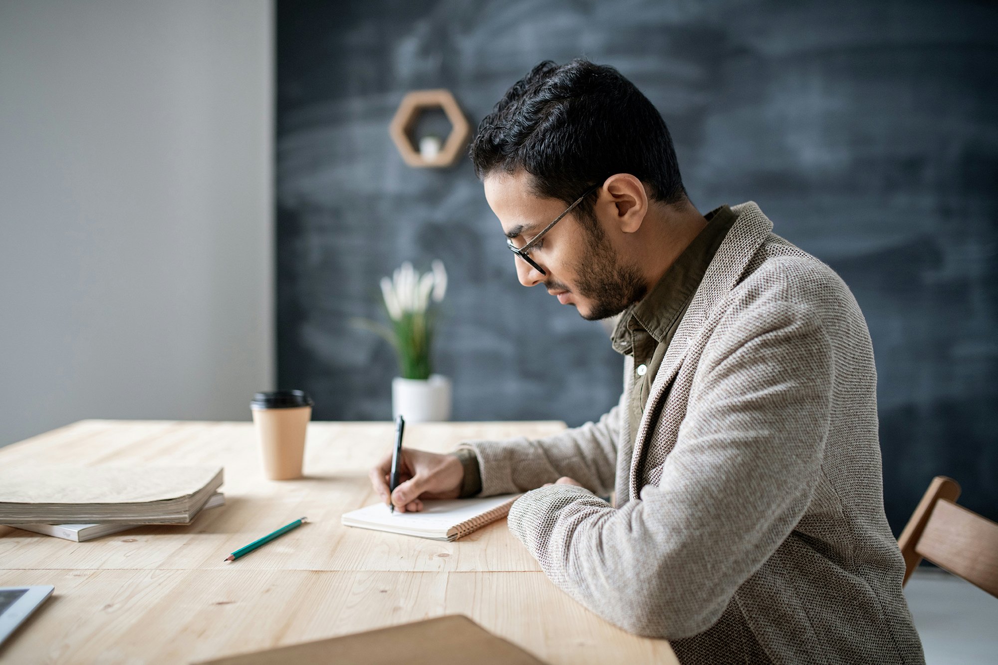 Teacher sitting at a desk writing in a notebook