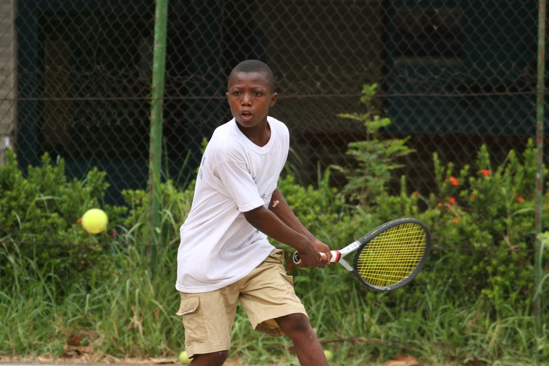 A young tennis player in Mali preparing to return the ball