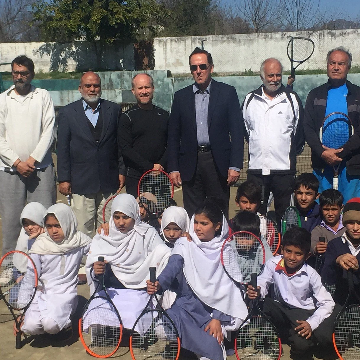 Students and coaches holding rackets at a school in Pakistan