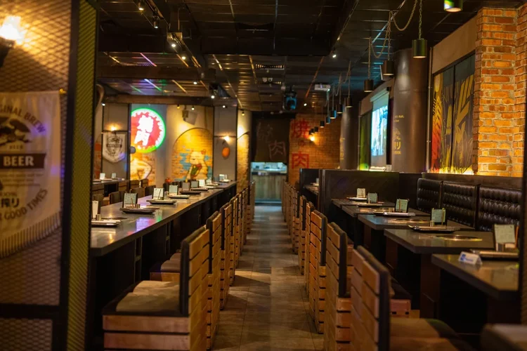 Interior of a Japanese restaurant with long counter seating and booth tables