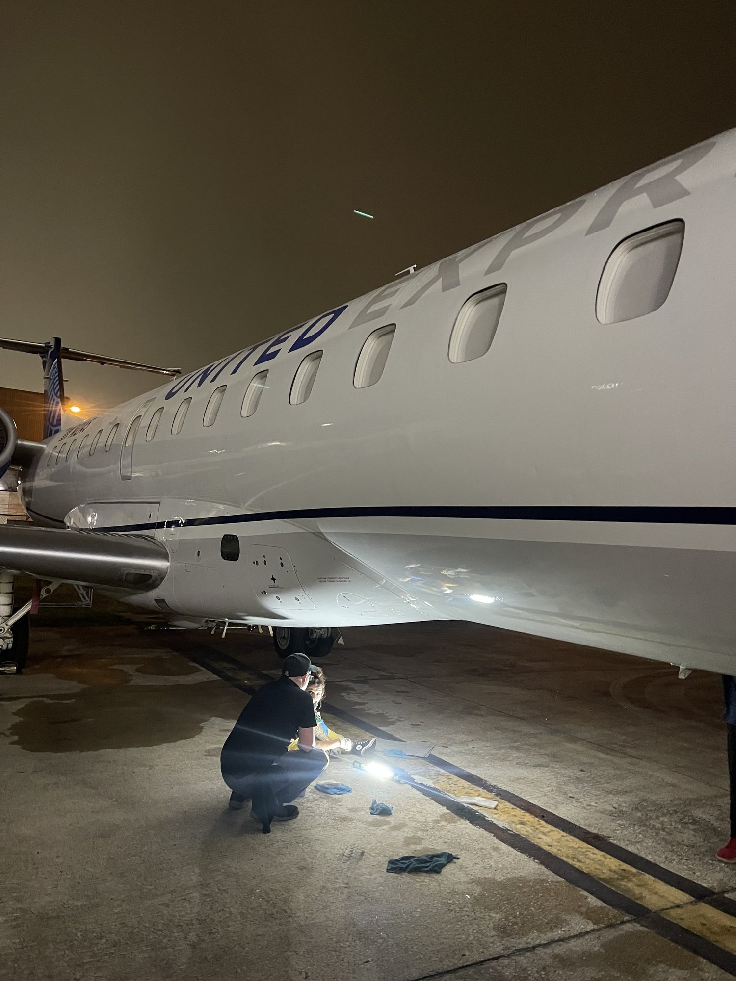Detailer working under an aircraft fuselage at night