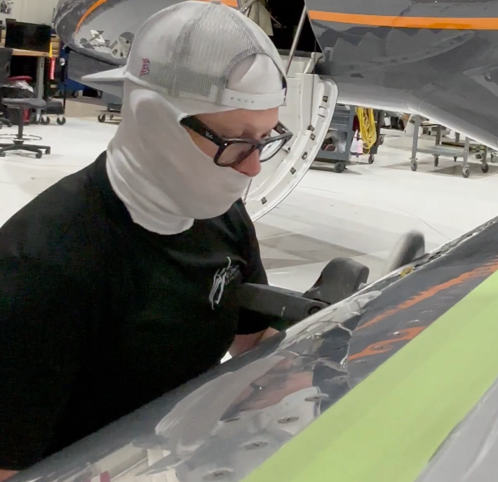 Detailer polishing an aircraft in a hangar