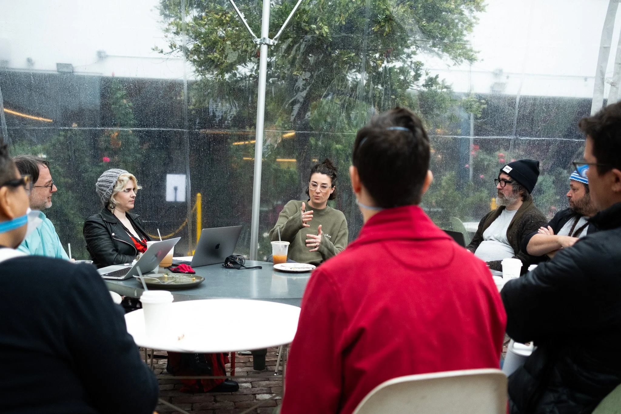 Production still: a director in a pink headband directs a scene on a colorfully lit set.
