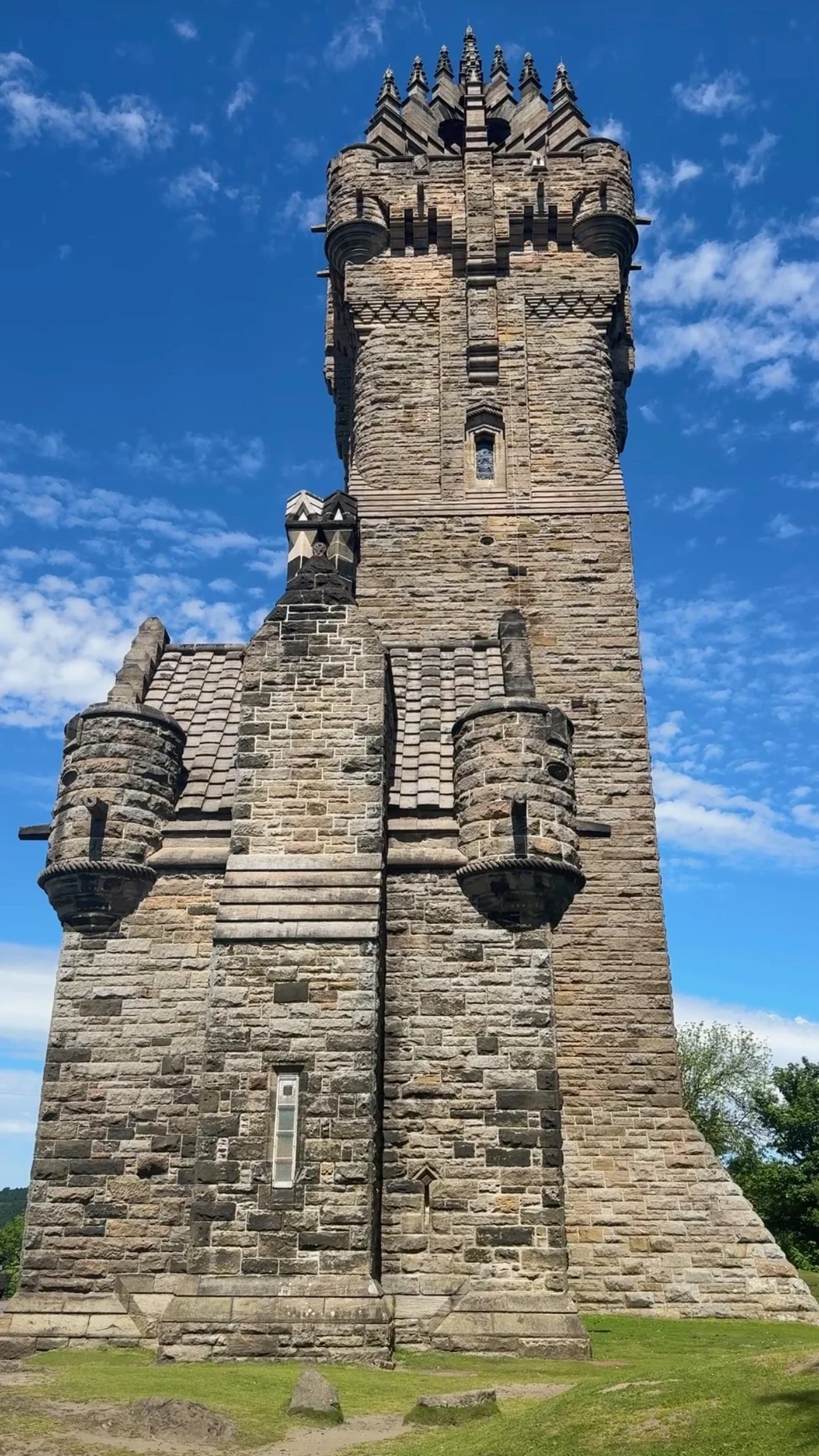 The National Wallace Monument rises above green trees against a blue sky.