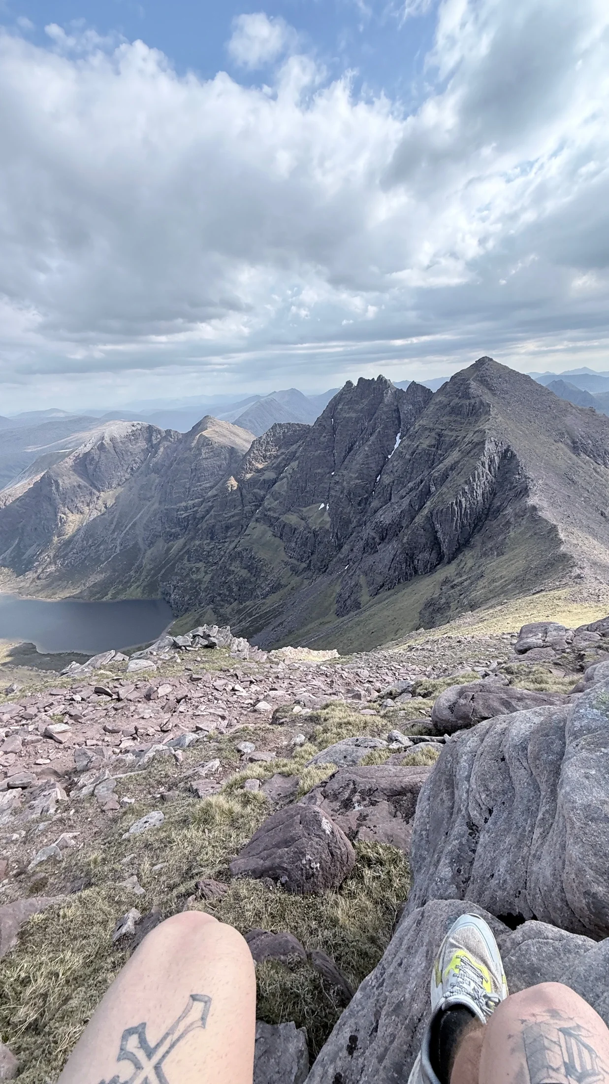 Trainers rest on rocky ground during a quiet pause above a Scottish mountain landscape.