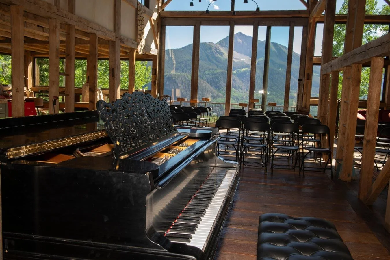The Mai House barn — grand piano, audience seating facing Mt. Sunshine through floor-to-ceiling windows