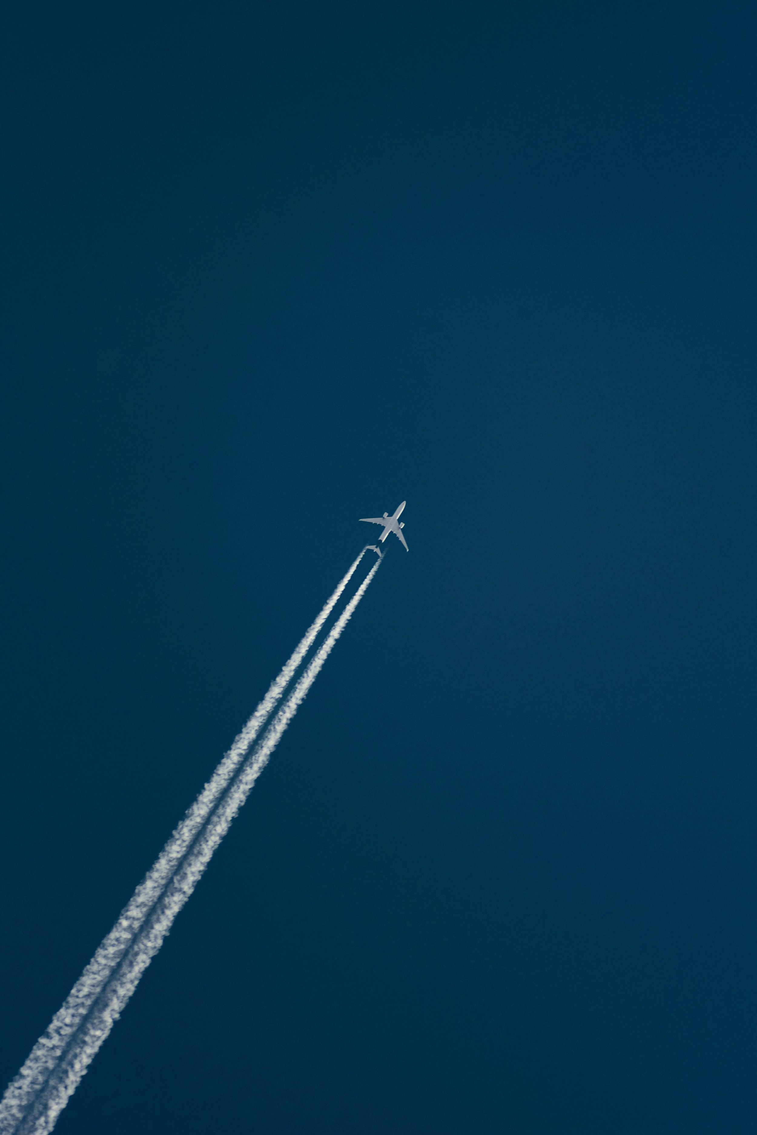 Plane with smoke trails on a deep blue sky